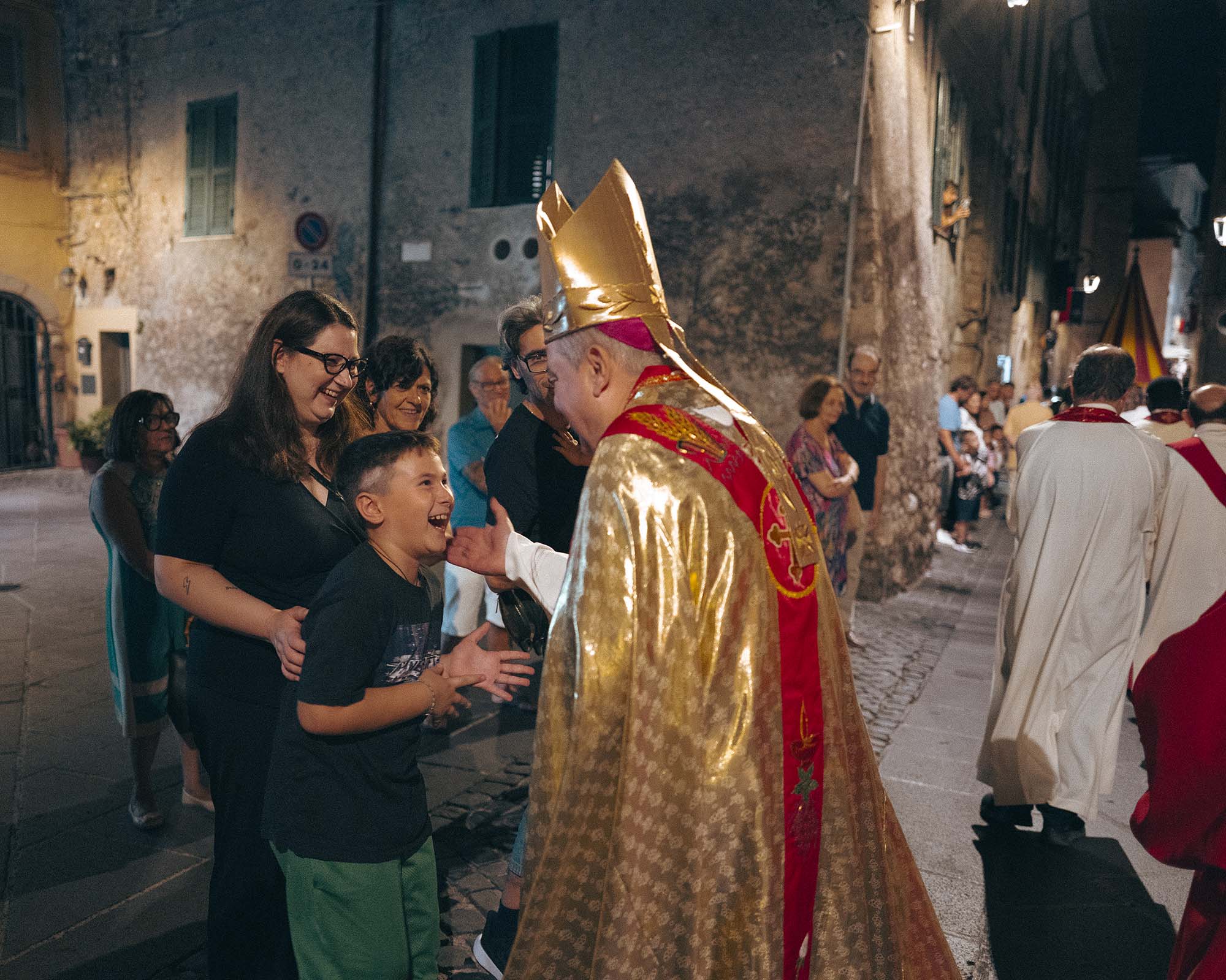 Il vescovo si ferma con un ragazzo, a metà processione